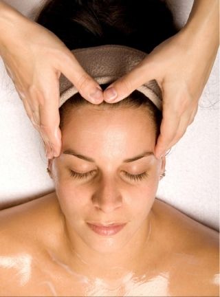Woman having a facial massage, eyes closed, fingers on her temples